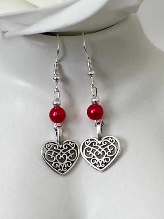 two heart shaped earrings with red beads hanging from them