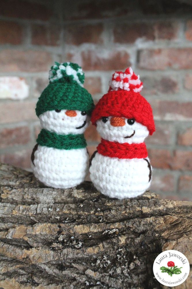 two crocheted snowmen sitting on top of a log