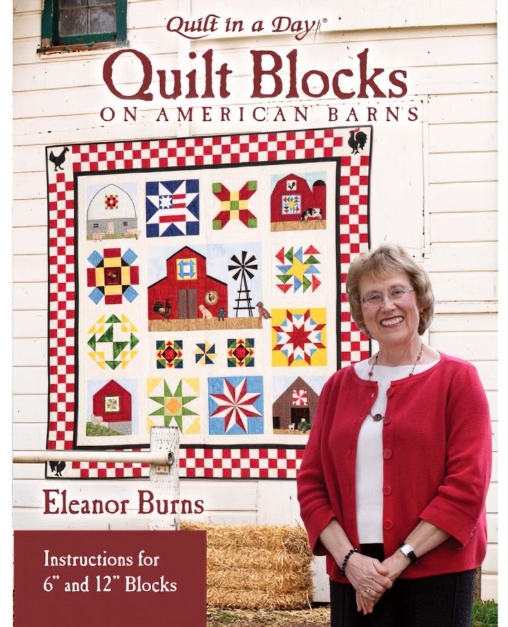 an older woman standing in front of a quilt block on american barn's sign