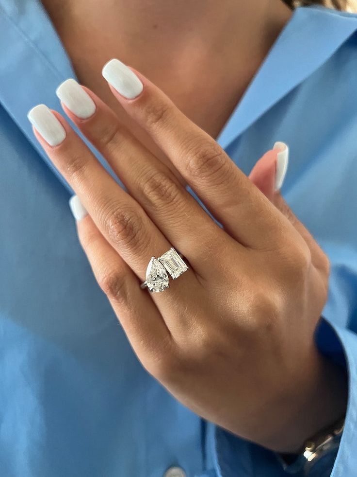 a woman's hand with white manicured nails and an engagement ring