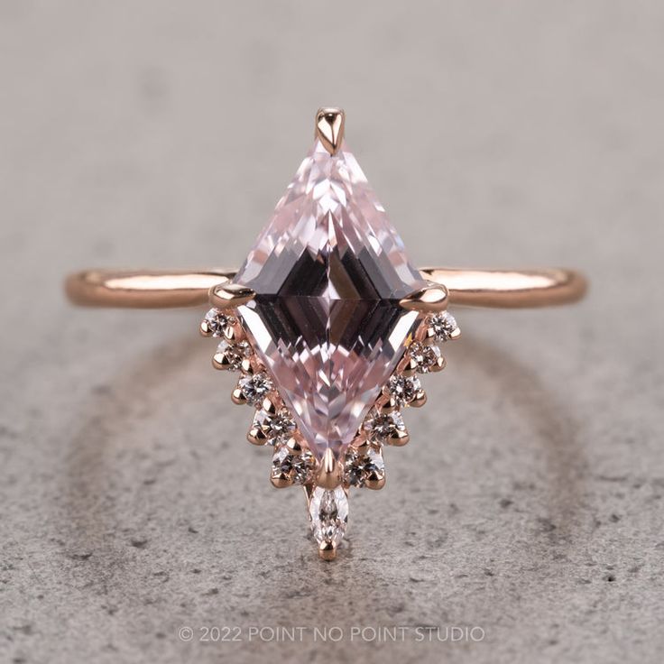 an engagement ring with a pink diamond and white diamonds on the side, set in 18k rose gold