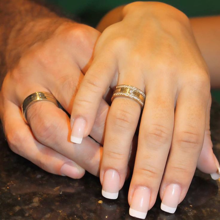 two hands holding each other with wedding rings on their fingers and gold bands around them