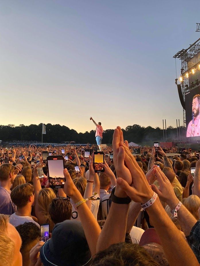 a crowd of people holding up cell phones in front of a stage with a man on it