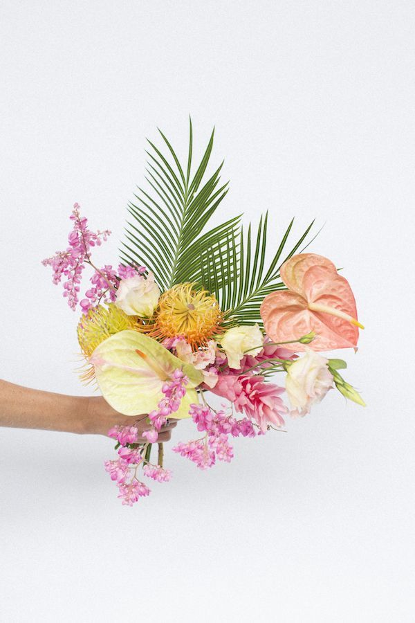 a hand holding a bouquet of flowers on a white background with pink and yellow colors