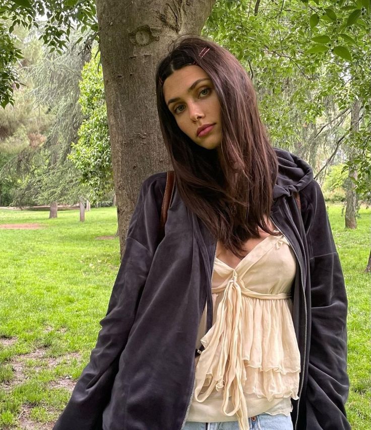 a woman standing next to a tree in a park