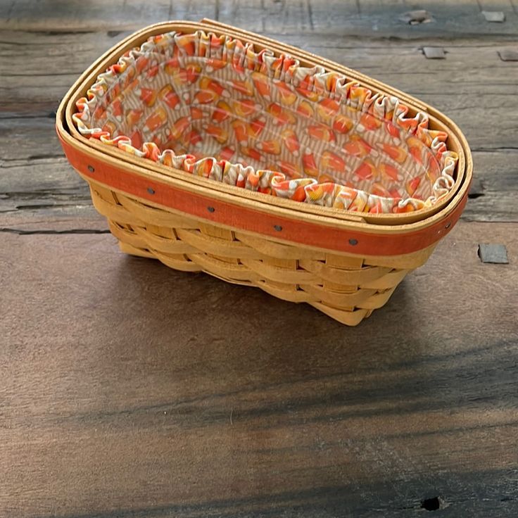 a wicker basket sitting on top of a wooden table next to an orange and white cloth