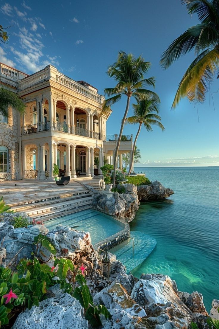 a large house with a pool in front of the water and palm trees around it