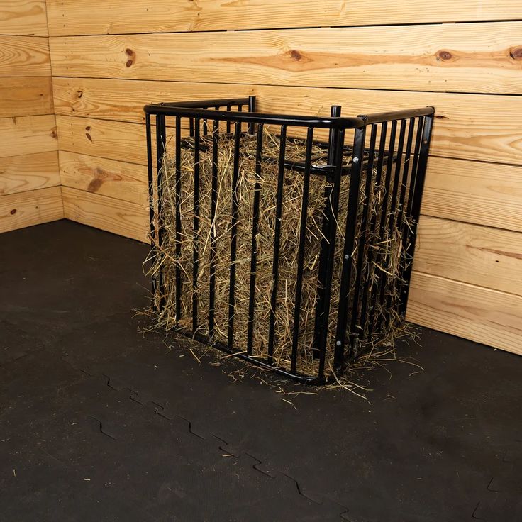 hay in a metal cage next to wooden walls