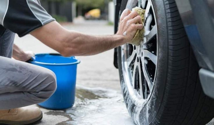 a man is washing his car with a sponge