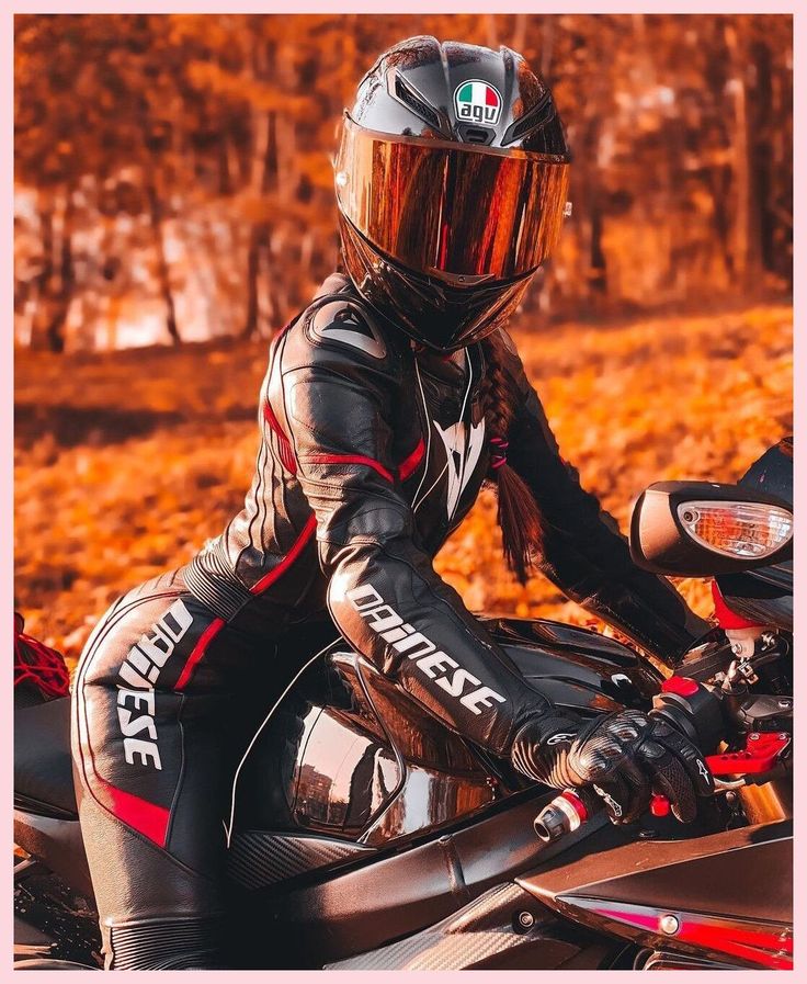 a person wearing a helmet sitting on a motorbike in the fall leaves,