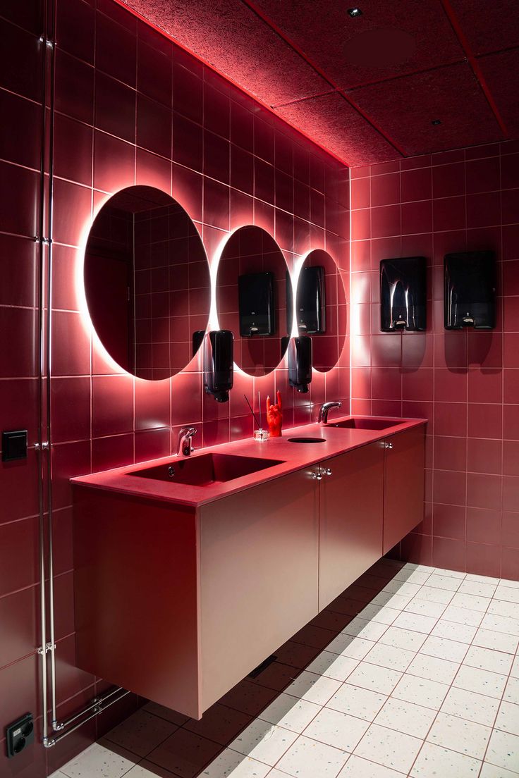 a red bathroom with three sinks and mirrors