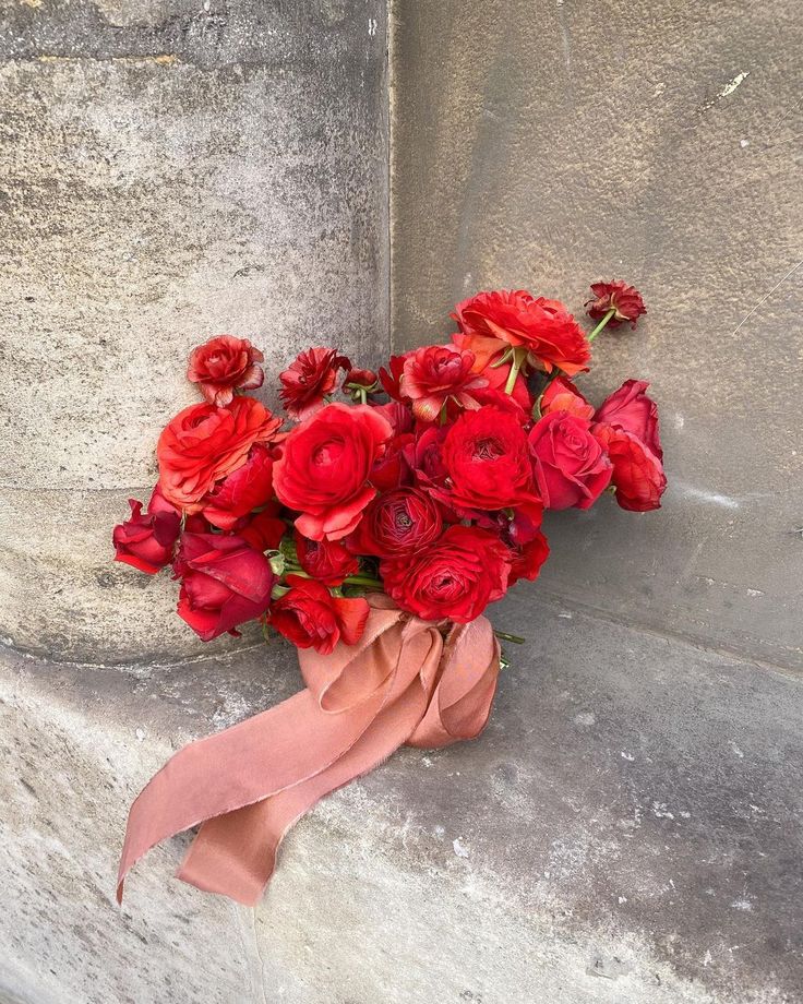 a bouquet of red flowers sitting on top of a cement wall