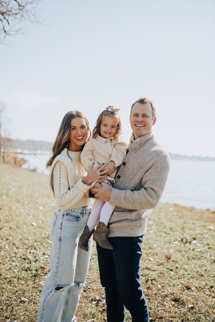 a man, woman and child standing in front of the water