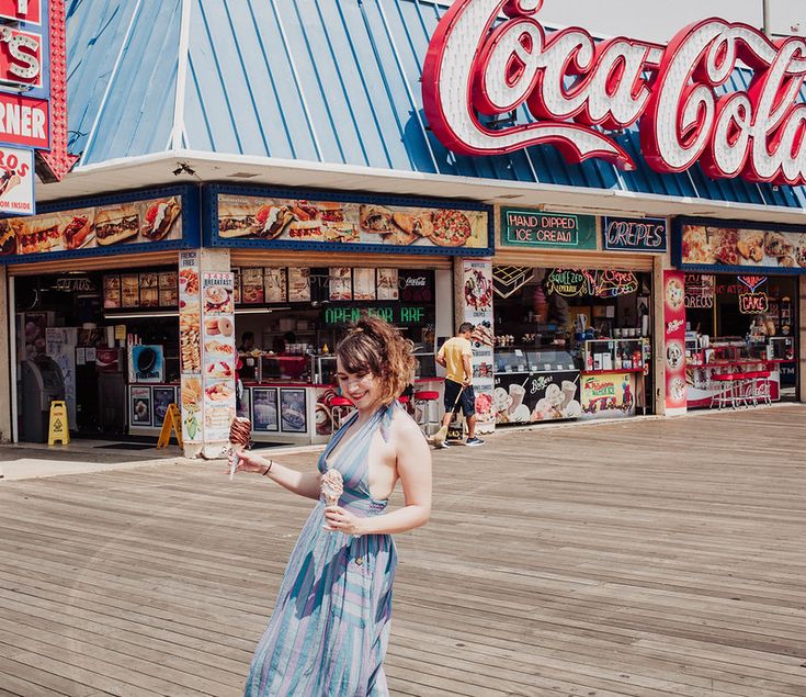 a woman in a dress is standing on the boardwalk