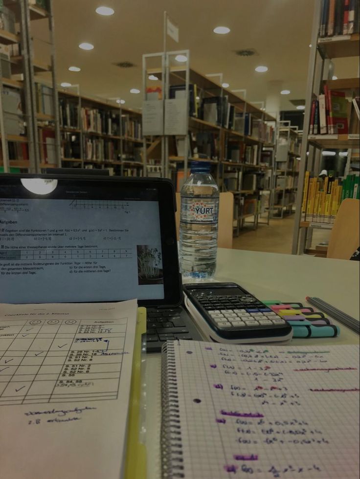 an open laptop computer sitting on top of a desk next to a calculator