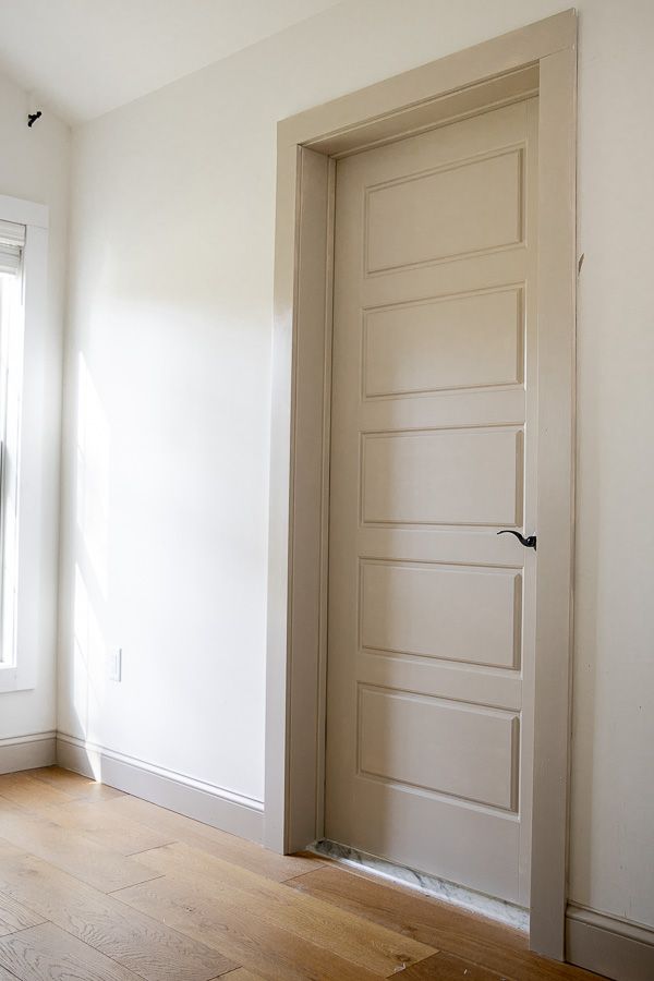 an empty room with a closed door and hard wood floor