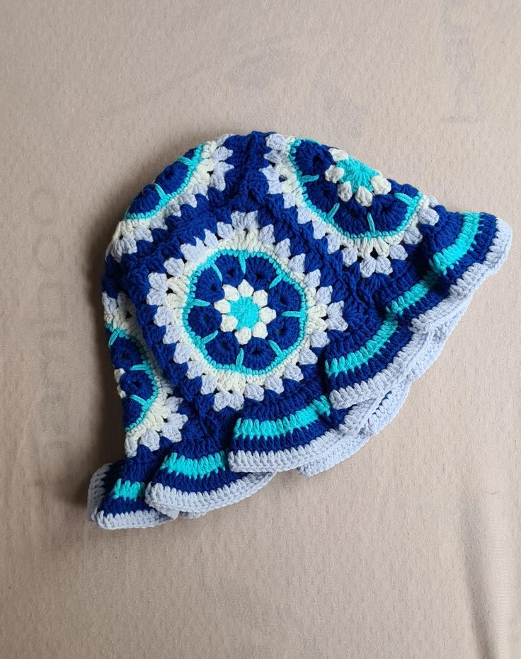 a blue and white crocheted hat laying on top of a bed