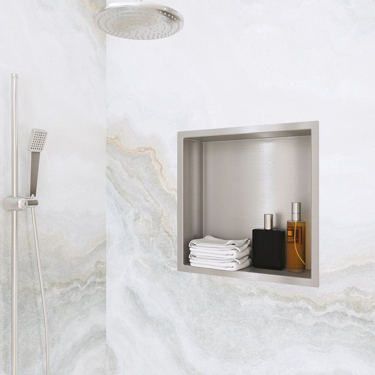 a bathroom with white marble walls and flooring, including a shower head in the corner