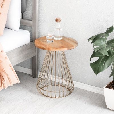 a small table with a glass bottle on it next to a potted plant and pillow