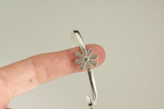 A 15mm lovely daisy flower like center piece on this cuff bracelet. The cuff  is about 3.25 x 1.65mm. Choice of mirror polish  or matte finish.handmade with 925 solid sterling silver.--------------How to measure?measure your wrist with a cord before the bone and then measure the cord with a ruler. Add  1/4" to 1/2" for a tight look or 3/4" to 1" for a loose look.Measures:S - bracelet measures 5" plus 1" gap = total 6"M - bracelet measures 5.5" plus 1" gap = total 6.5"L - bracelet measures 6" plu Silver Sterling Silver Flower Bracelets, Sterling Silver Flower-shaped Bracelets, Silver Sterling Silver Bracelets With Flower Shape, Silver Sterling Silver Bracelets With Flower Design, Silver Sterling Silver Flower-shaped Bracelets, Silver Flower-shaped Sterling Silver Bracelets, Dainty Silver Flower Bracelets, Dainty Sterling Silver Bangle, Silver Flower Cuff Bracelet For Gift