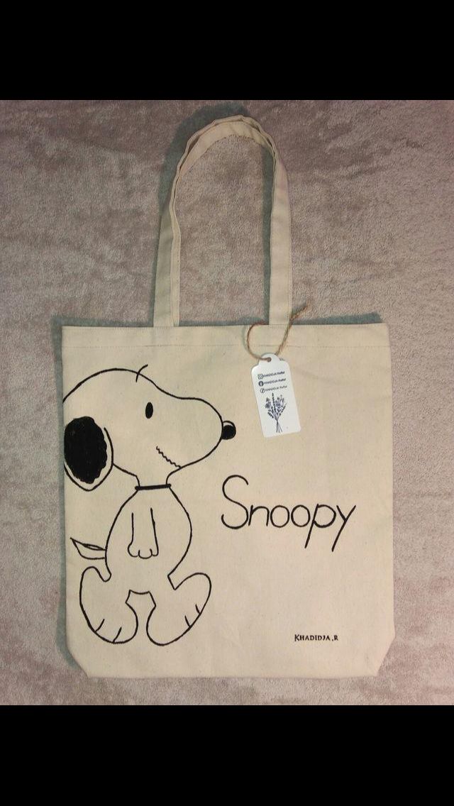 a snoopy bag is on the floor with a tag hanging from it's side