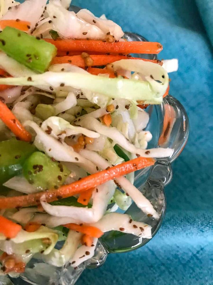 a glass bowl filled with carrots, celery, and sprouts