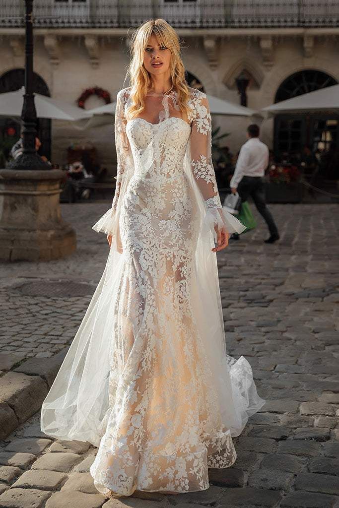 a woman in a wedding dress standing on a cobblestone street