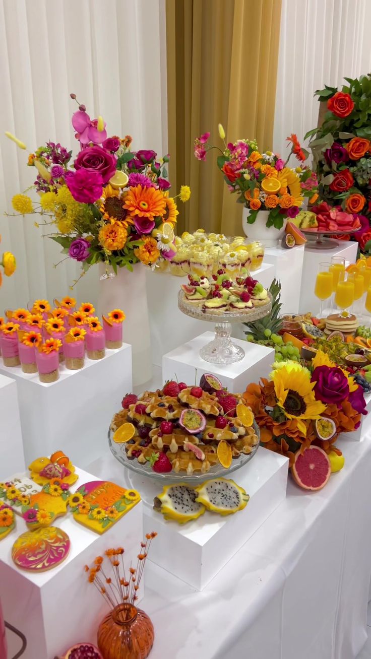 a table topped with lots of different types of desserts and flowers in vases