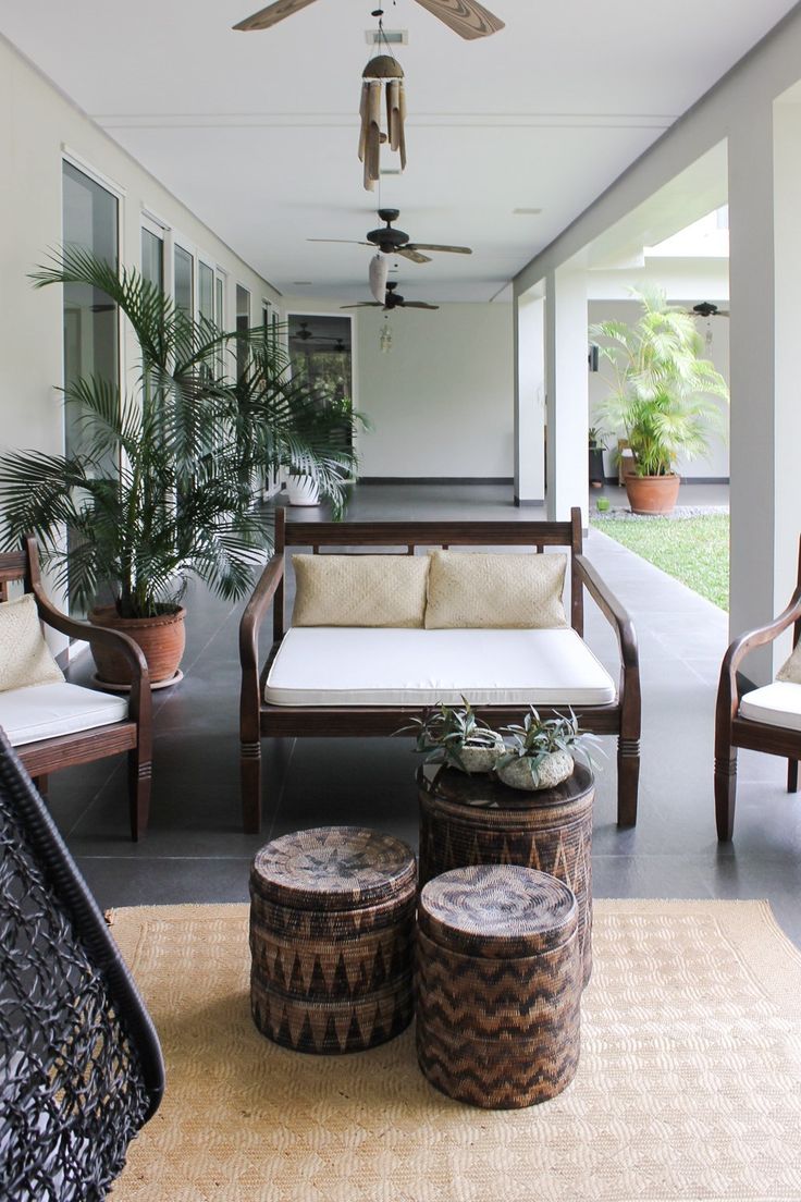 an outdoor living area with couches, tables and plants on the side walk way