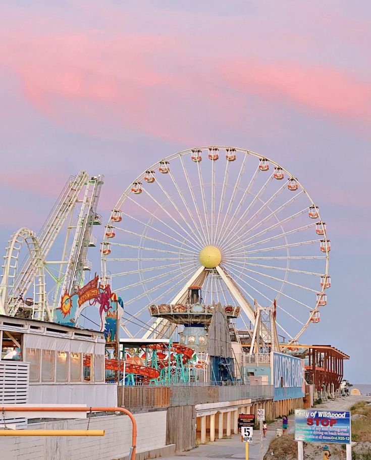 a ferris wheel sitting on top of a pier next to the ocean