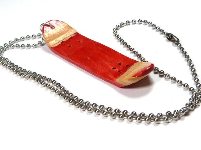 a necklace with a red object on it's side hanging from a ball chain