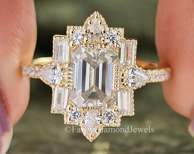 a woman's hand holding a ring with an emerald and white diamond in it