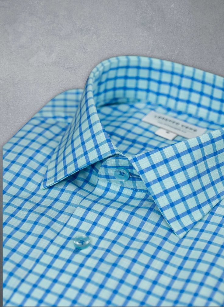 The dreamy feel of the super soft Alexander in Aqua Blue Plaid Shirt evokes the relaxed Mediterranean lifestyle, with its shimmering shades of Blue. Deliberately detailed with well-thought-out accoutrements such as matching blue buttons and button threads lend a custom look to this beautiful shirt. Can be dressed up under a blazer or worn untucked, for a more casual, after-hours look. The Alexander is the trimmest of all our fits, calibrated to accentuate a lean, athletic body type. • Trimmest F Summer Blue Dress Shirt With Buttons, Light Blue Summer Tops With Button Cuffs, Fitted Blue Tops With Button Cuffs, Fitted Blue Top With Button Cuffs, Summer Light Blue Dress Shirt With Button Closure, Blue Relaxed Fit Button-up Dress Shirt, Blue Relaxed Fit Dress Shirt For Spring, Light Blue Tops With Button Cuffs And Spread Collar, Classic Blue Shirt For Summer