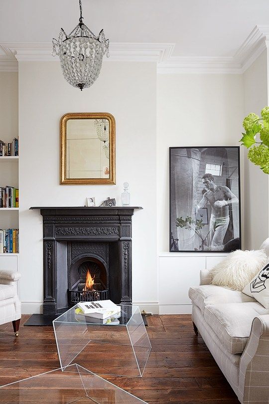 a living room filled with furniture and a fire place under a chandelier above a fireplace