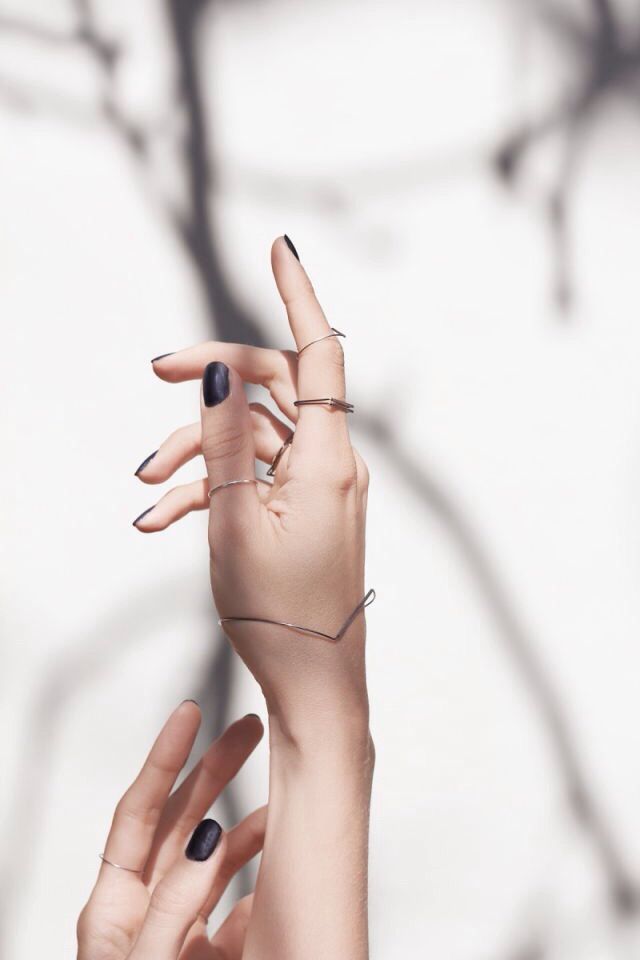 two hands reaching up towards each other with black and white manicures on their fingers