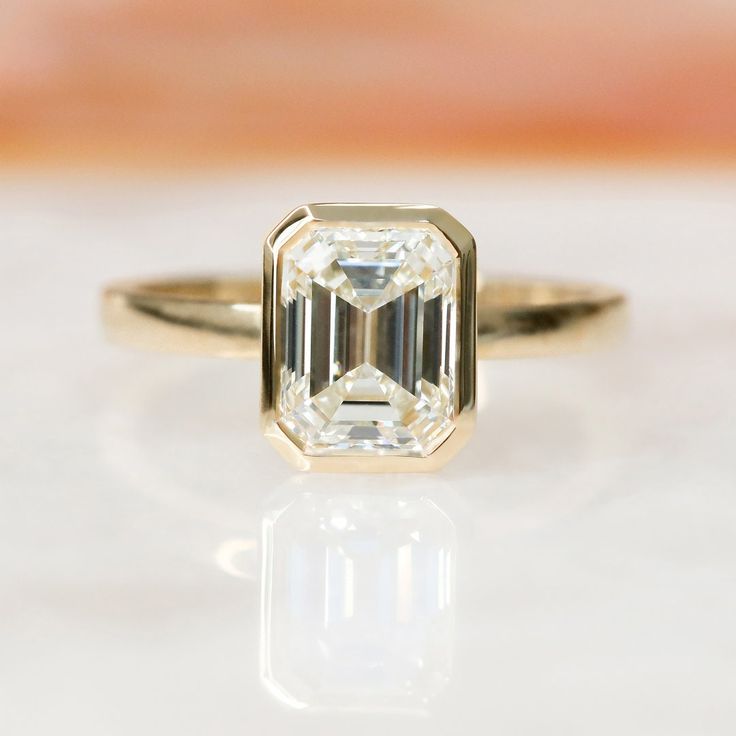 an emerald cut diamond sits on top of a white surface