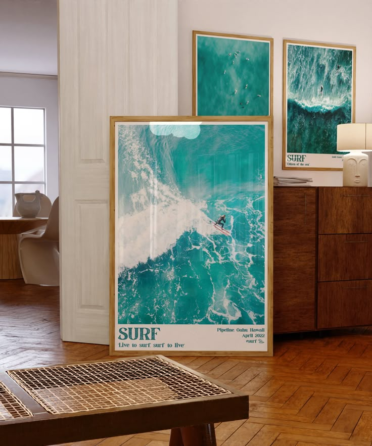 there is a surf poster on the wall next to a coffee table and dresser in this room