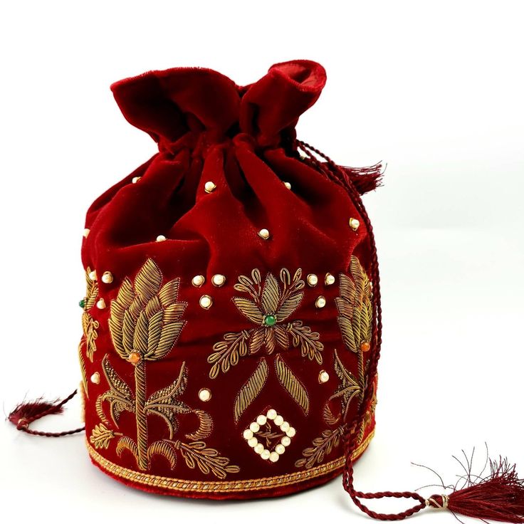 "Look your best wearing this luxurious black velvet pouch bag, exquisitely embroidered with glittery metallic red threads and genuine semi precious stones. It is certain to bring you compliments. Perfect color for Indian wedding! Expertly hand embroidered by third generation master zardozi artisans. Of heirloom quality. - Measures approx 9\" tall, base is 6\" across. - Useable interior space is 6\" x 6 \". - Rigid bottom and 2\" base, so bag sits nicely. - Wrist cord with tassel, 6 in. drop - Ad Luxury Red Bucket Bag With Removable Pouch, Elegant Embroidered Red Potli Bag, Bollywood Style Embroidered Evening Potli Bag, Elegant Red Embroidered Potli Bag, Traditional Evening Pouch For Festivals, Traditional Evening Pouch For Festive Occasion, Traditional Embroidered Evening Bags, Traditional Evening Festive Pouch, Luxury Potli Bag With Handwork For Gift