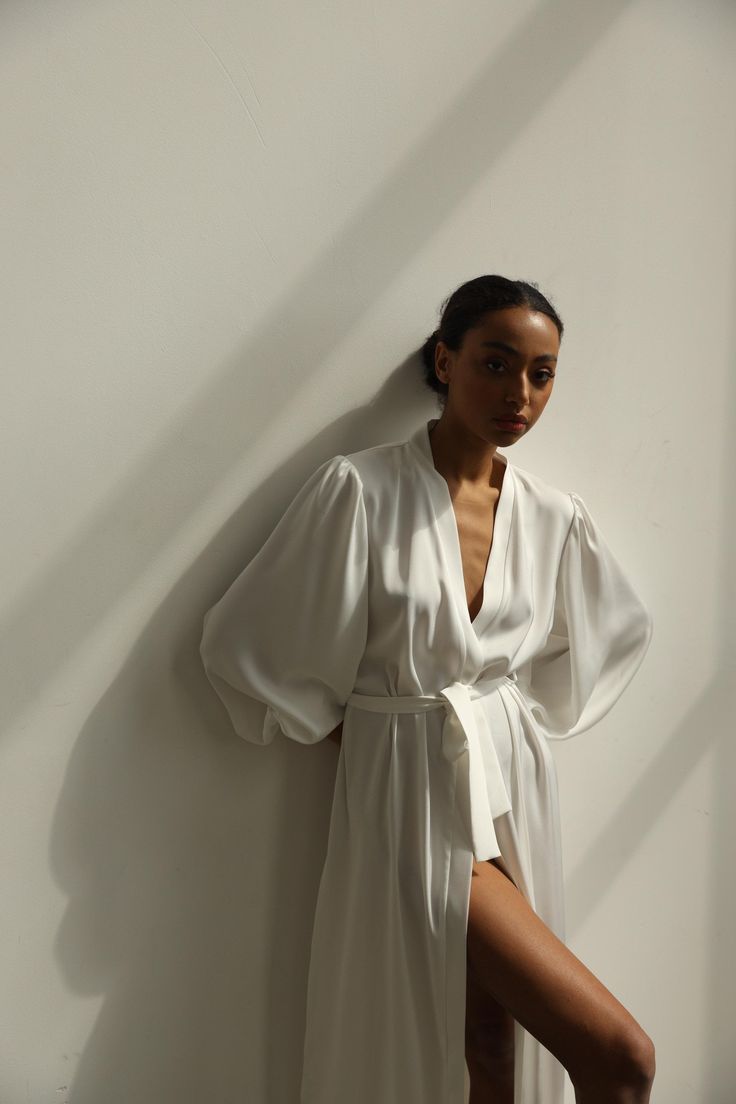 Our long bridal silk robe with wide long sleeves. It could be made of satin or pure mulberry silk. The robe is both casual and elegant, you may wear it on the hen party or spontaneously around your home on a daily basis. It is also an amazing outfit for your vocation, to wear it on the beautiful beach or by the pool as a cover up. -Our model wears size XS, her measurements are 82/61/87 cm and she is 172 cm tall. -Attached with belt. -Arrives beautifully packaged in tissue paper with ribbon -Leng Satin V-neck Robe For Daywear, White V-neck Robe For Sleep, Elegant V-neck Kimono For Daywear, Long Sleeve Satin Robe For Summer, Satin V-neck Daywear Robe, Long Sleeve Satin Summer Robe, Elegant Summer Robe With Kimono Sleeves, Elegant Summer Wrap Sleepwear, Elegant Open Front Summer Robe