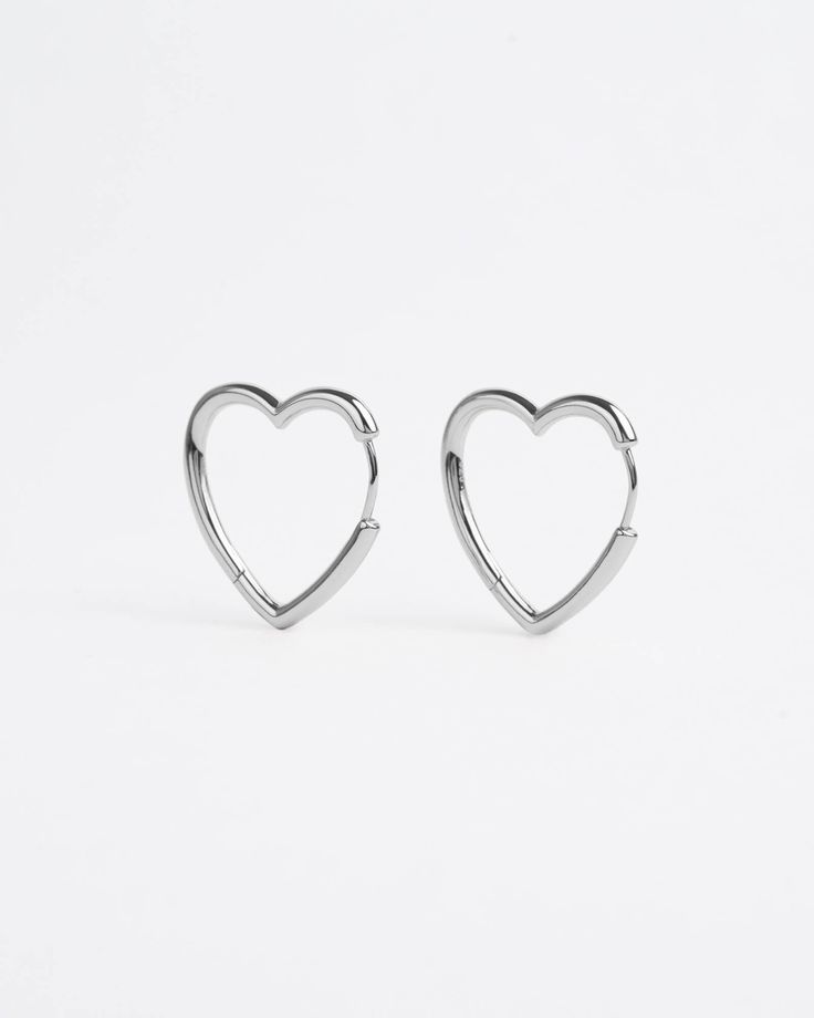 Devotional holds honoured. For all romantiques to wear love lite. Heart-shaped earrings with a seamless clicker mechanism and a high-polished finish. Available in 3 hoop sizes – small for a closer fit, medium to match any style or large for louder looks. Sold as a pair. Style & Material Style: Hoop Earrings Base material: 925 silverNickel-free: Yes Gold Coating: 14K gold plating Silver Coating: None Measurements (per piece) Small Height: 10mm Thickness: 2.4mm Weight: 1.4 grams Medium Height: 14m Hypoallergenic Heart Shaped Huggie Earrings, Hypoallergenic Heart Huggie Earrings, Silver Heart Charm Huggie Earrings, Valentine's Day Nickel-free Huggie Hoop Earrings, Silver Huggie Earrings With Heart Charm, Silver Huggie Earrings For Valentine's Day Elegant Style, Silver Huggie Earrings With Heart Charm For Anniversary, Minimalist Sterling Silver Hoop Earrings For Valentine's Day, Hypoallergenic Heart-shaped Huggie Earrings In Sterling Silver