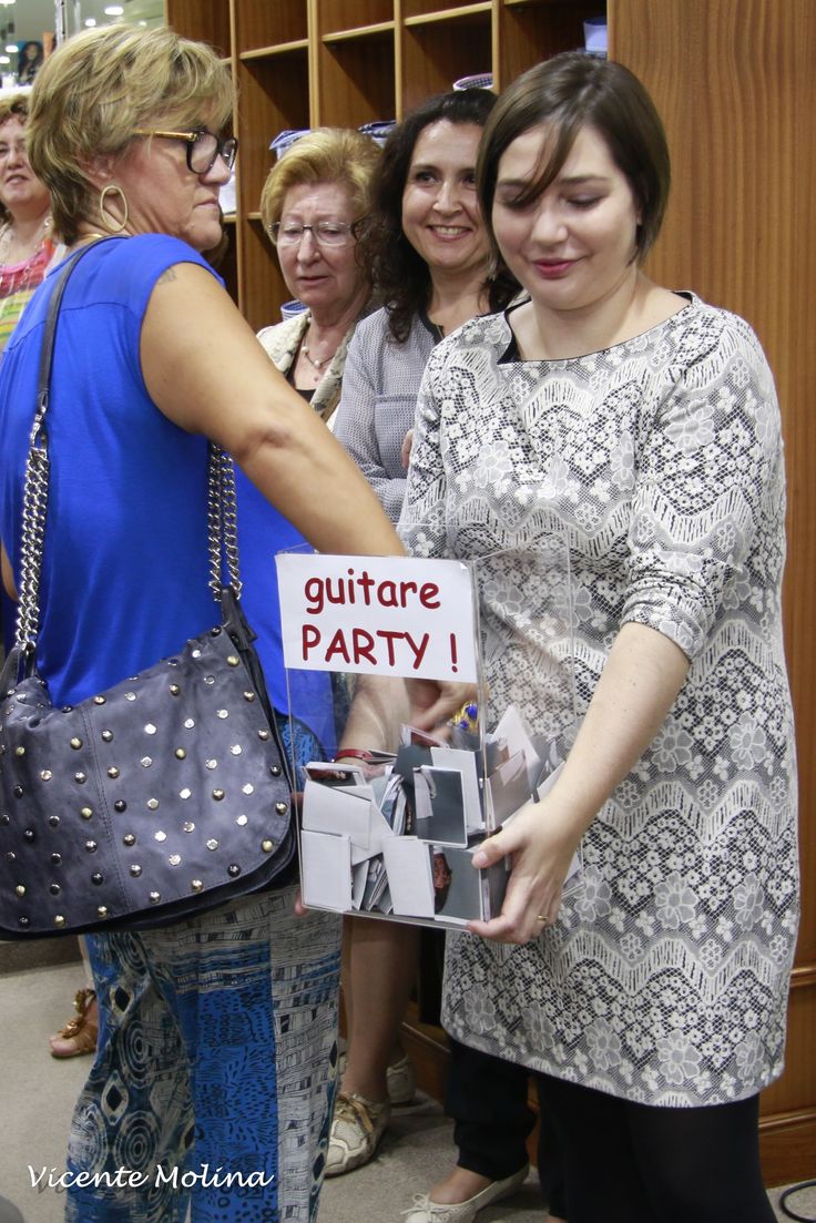 a group of women standing next to each other in front of a book shelf with a sign that says guitar party