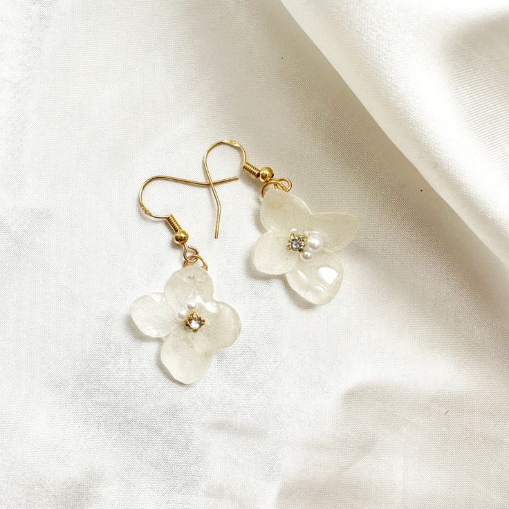 Elevate your style with new enchanting, handmade from real hydrangea flower earrings with a shinny rhinestone for a touch.  Each delicate petal is meticulously encased in resin, capturing the eternal beauty of nature. Adorned with hypoallergenic 18k Gold-plated hooks, these earrings are a perfect blend of elegance and nature's allure, making them a must-have addition to your jewelry collection.  Embrace timelessness and beauty. Flower-shaped Crystal Earrings For Gift, Flower Shaped Crystal Earrings For Gift, Gold Plated Flower Charm Earrings For Wedding, Feminine Gold Jewelry With 3d Flowers, White Gold Plated Flower Earrings For Wedding, Delicate White Crystal Earrings For Gift, Gold Feminine Flower Earrings With 3d Flowers, Gold Elegant Flower Earrings With 3d Flowers, Elegant Gold Flower Earrings With 3d Details