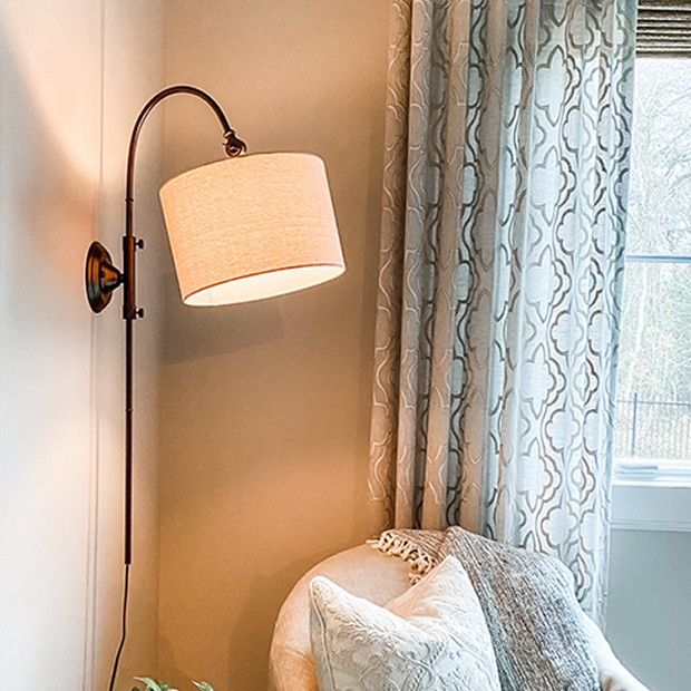 a living room with a chair and lamp next to a window in front of it