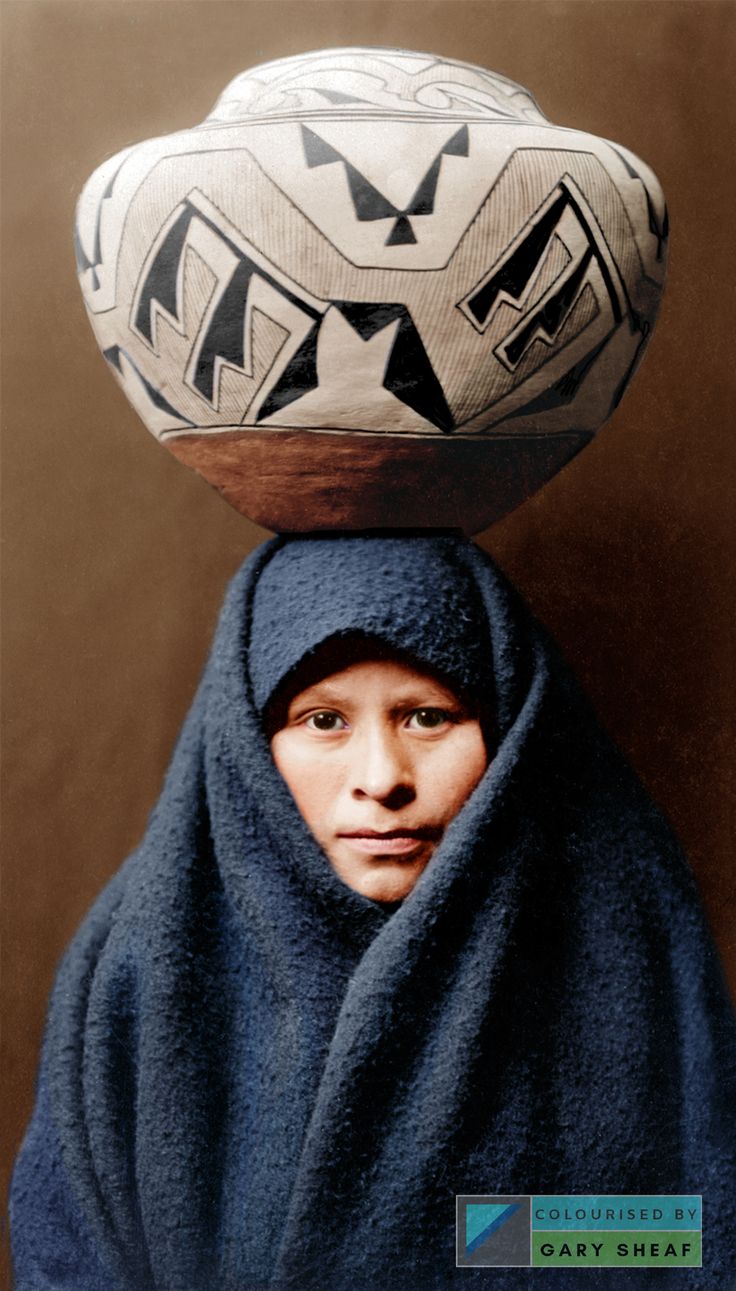 a woman wearing a blue shawl with a large bowl on top of her head