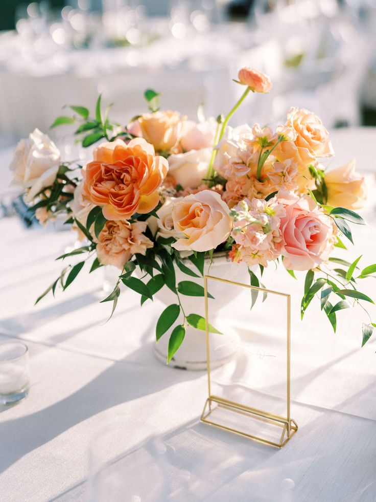 a vase filled with lots of flowers on top of a white tablecloth covered table