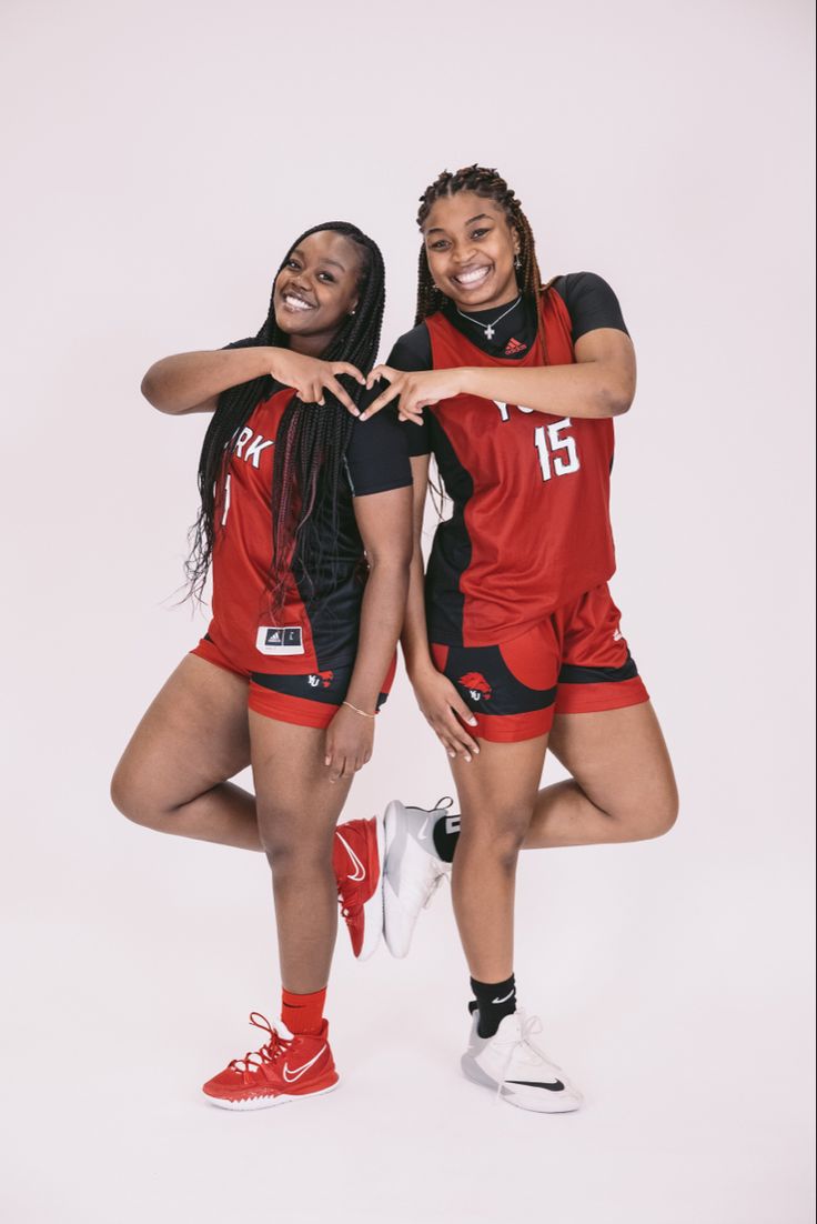 two women in red and black uniforms are posing for a photo with their arms around each other