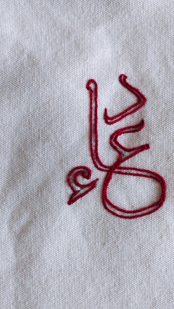 a close up of a red thread on a white cloth with the word love spelled in it