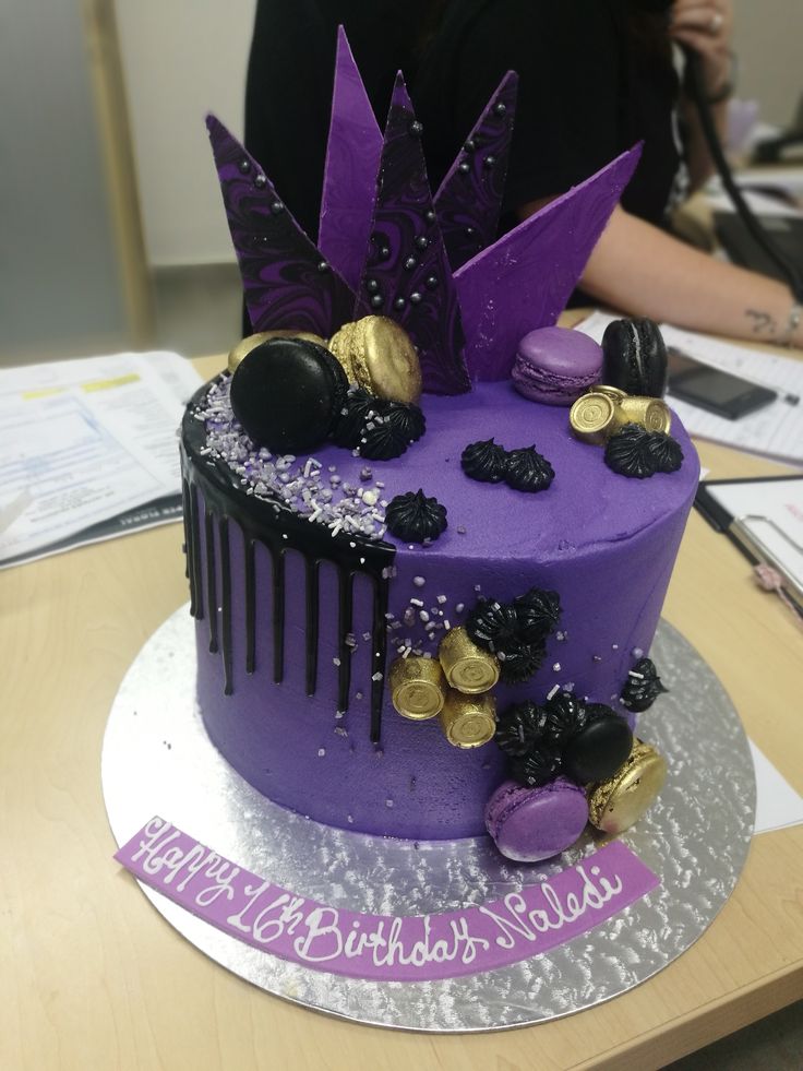 there is a purple cake with gold decorations on the top and bottom, sitting on a table