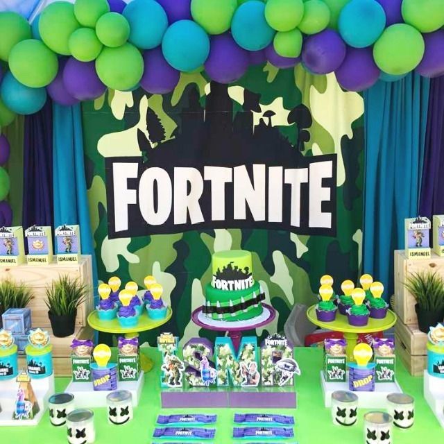 a table topped with lots of cakes and desserts covered in green, purple and blue balloons