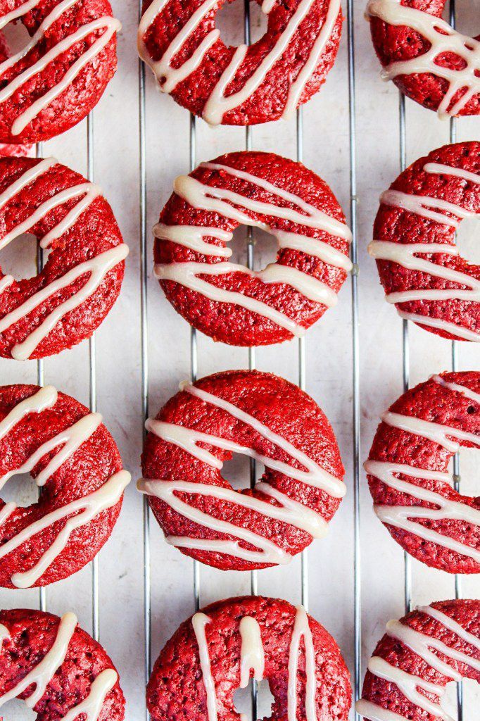 red velvet donuts with white icing on a cooling rack